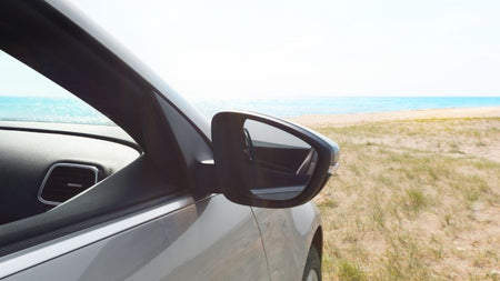 Lateral de carro numa zona alta com o mar à frente, para retratar o tema dos cuidados com o carro no verão