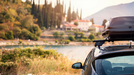 Carro com objeto no tejadilho e uma paisagem à sua frente para retratar o tema sobre cuidados com o carro antes de viajar